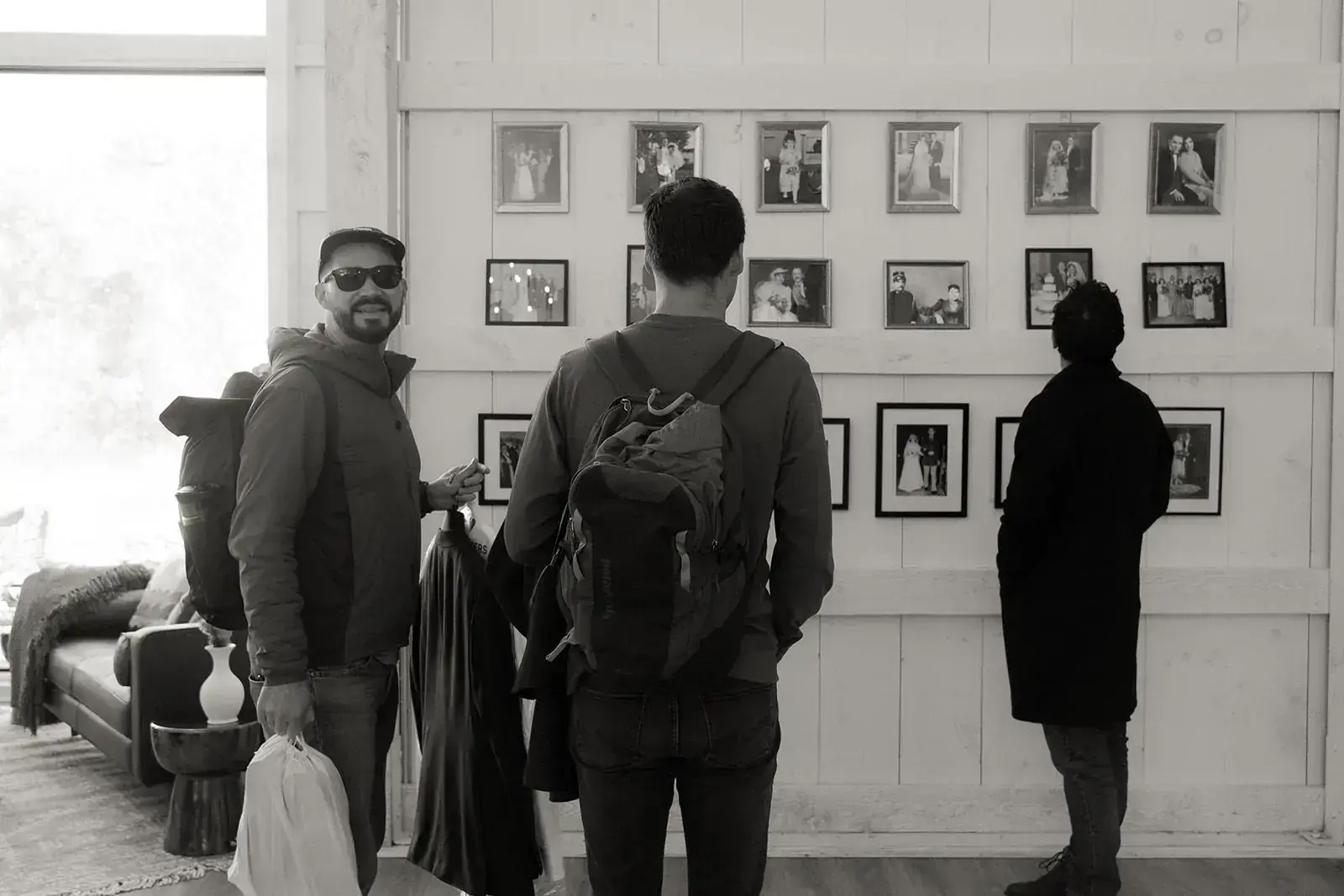 Guests arriving and taking in the wedding photo wall inside the barn