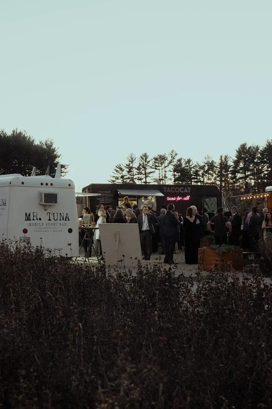 Food trucks lit up at dusk with guests filling the courtyard