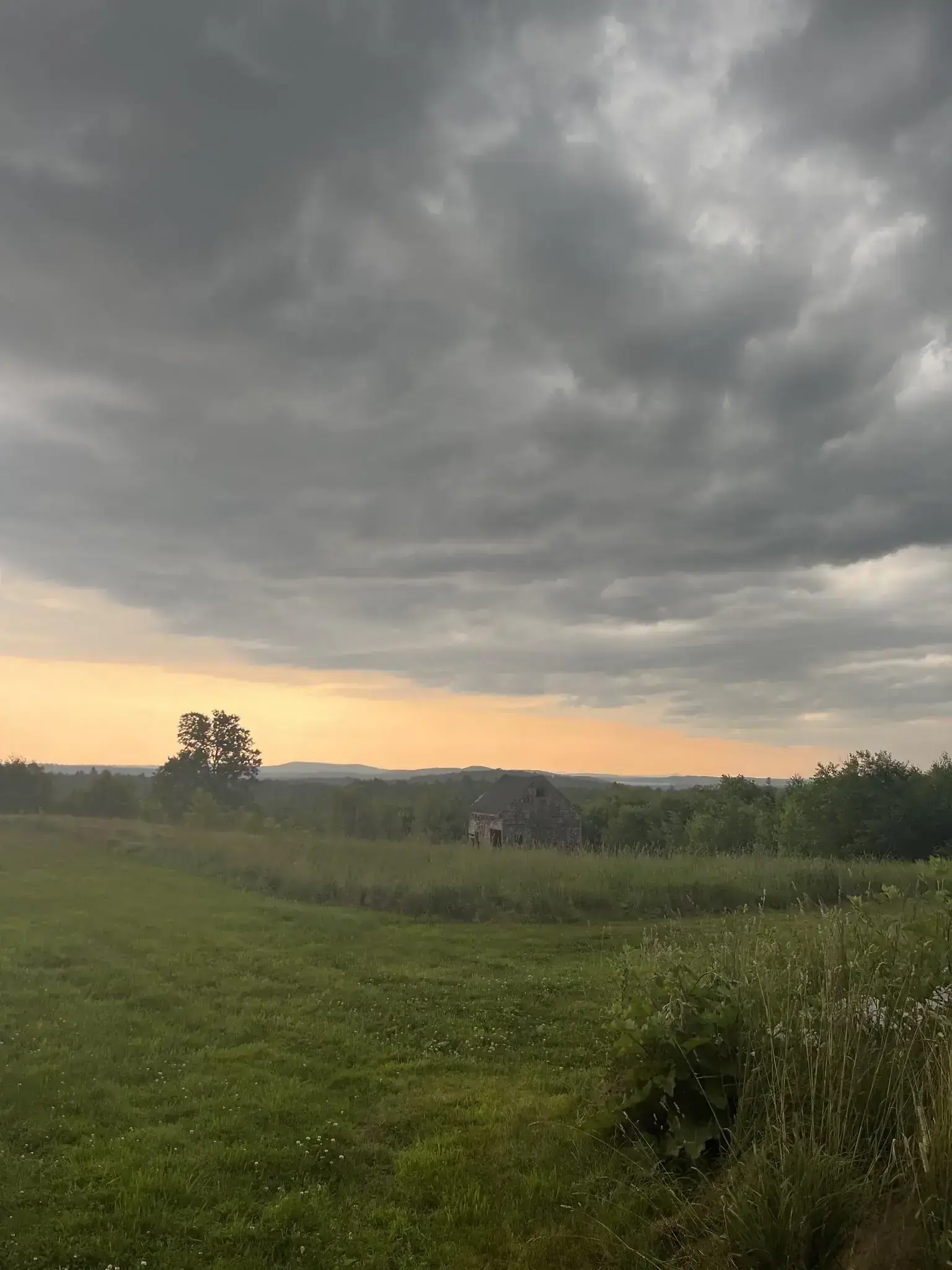 The barn at South Road Farm seen across the field at dusk, storm clouds overhead